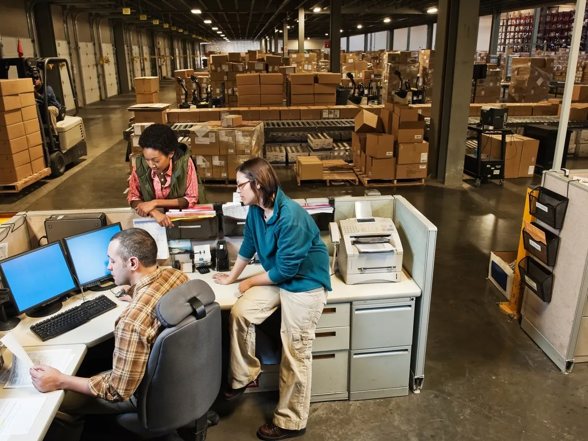 Two operations workers reviewing a shipping document on a computer